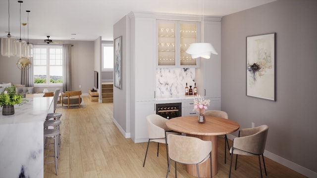 dining area with ceiling fan, light hardwood / wood-style floors, and bar