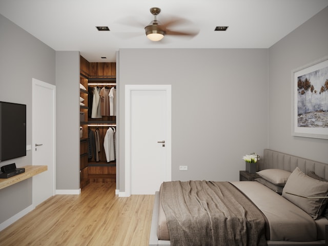 bedroom with a walk in closet, ceiling fan, a closet, and light wood-type flooring