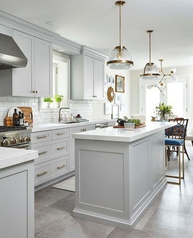 kitchen featuring tasteful backsplash, a kitchen island, wall chimney exhaust hood, and sink