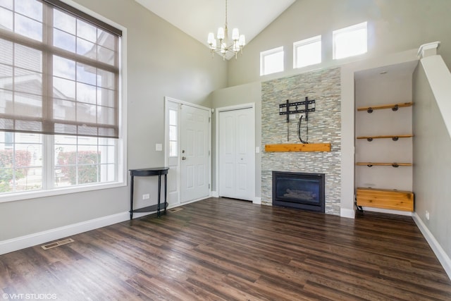 unfurnished living room with dark hardwood / wood-style flooring, built in shelves, high vaulted ceiling, a fireplace, and a chandelier