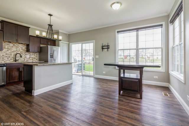 kitchen with appliances with stainless steel finishes, backsplash, dark hardwood / wood-style flooring, and pendant lighting