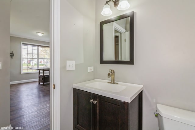 bathroom with toilet, vanity, ornamental molding, and hardwood / wood-style flooring