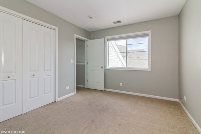 unfurnished bedroom featuring light carpet and a closet