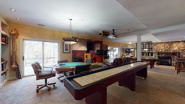 game room with carpet, a stone fireplace, ornamental molding, and decorative columns