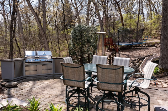 view of patio featuring grilling area, exterior kitchen, and a trampoline