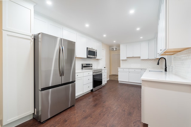 kitchen with stainless steel appliances, sink, backsplash, white cabinets, and dark wood-type flooring