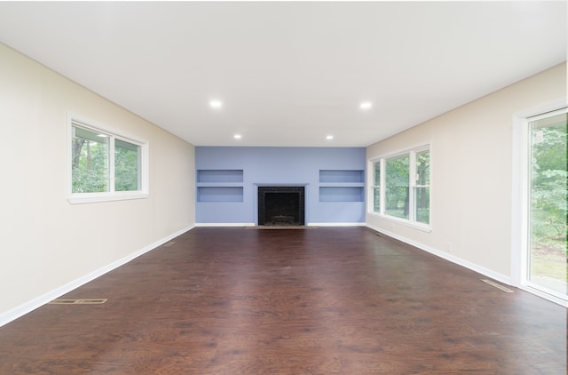 unfurnished living room with a fireplace, dark hardwood / wood-style flooring, and a healthy amount of sunlight