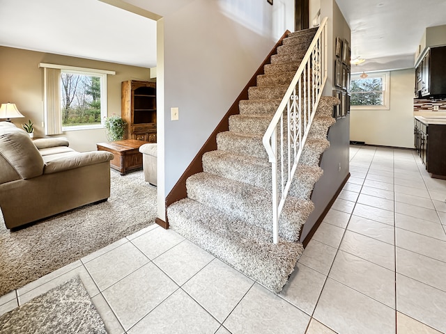 staircase featuring tile patterned flooring and ceiling fan