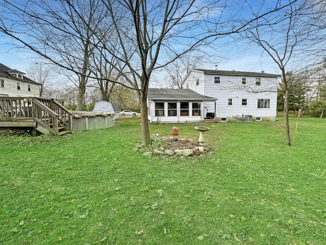 back of property featuring a lawn, a sunroom, and a wooden deck