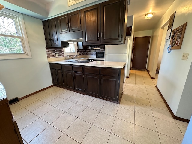 kitchen featuring tasteful backsplash, sink, light tile patterned flooring, and dark brown cabinets