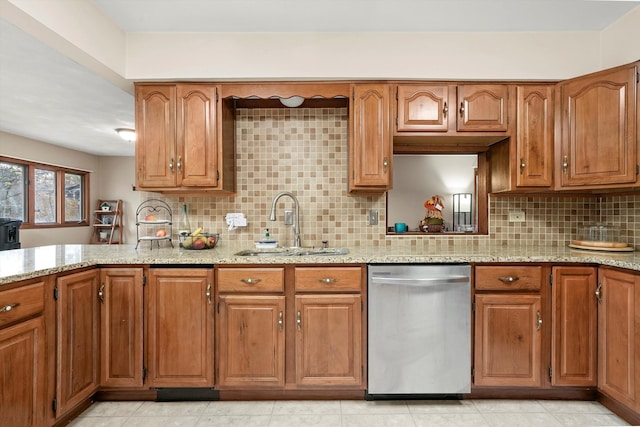 kitchen featuring tasteful backsplash, light stone counters, sink, and stainless steel dishwasher