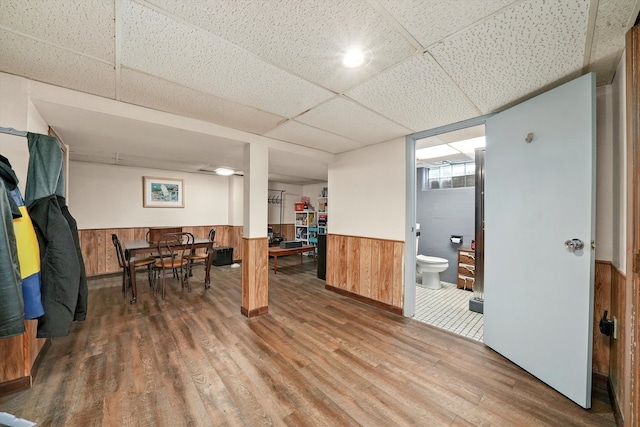 interior space with hardwood / wood-style flooring, a drop ceiling, and wood walls