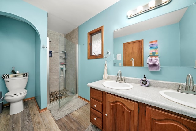 bathroom with toilet, vanity, wood-type flooring, and tiled shower