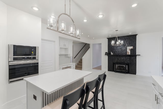 kitchen featuring a kitchen island, white cabinets, a high end fireplace, and stainless steel appliances