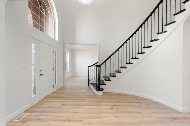 entryway with a towering ceiling and light hardwood / wood-style floors