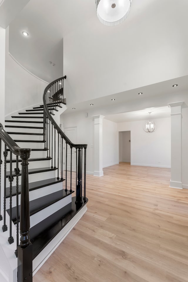 stairway with wood-type flooring, a chandelier, and decorative columns