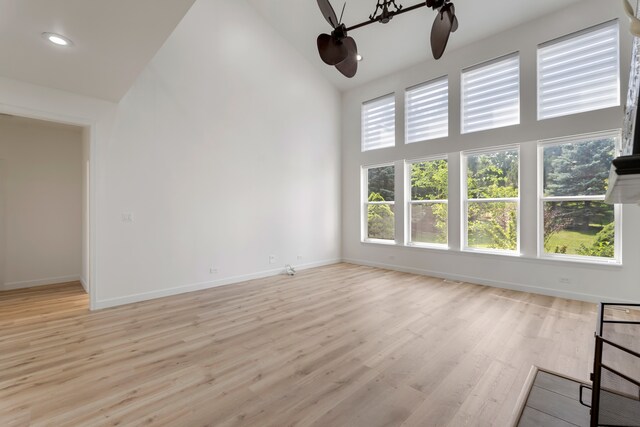 unfurnished living room with high vaulted ceiling, light wood-type flooring, and ceiling fan