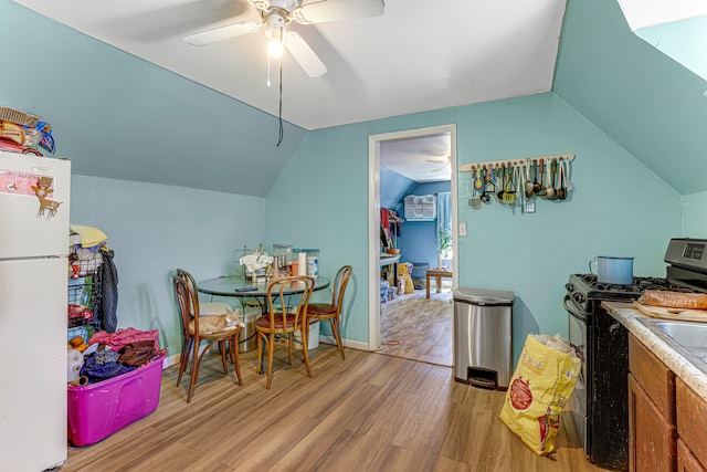 dining area with light wood-type flooring, vaulted ceiling, and ceiling fan