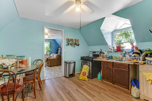 kitchen with lofted ceiling, stainless steel gas stove, ceiling fan, dark brown cabinets, and light wood-type flooring