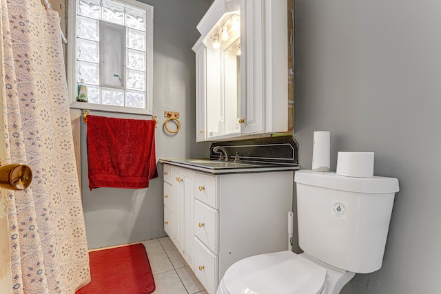 bathroom with toilet, vanity, and tile patterned flooring