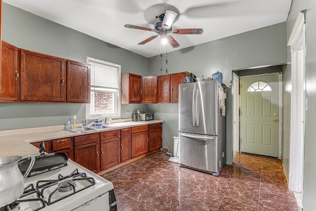 kitchen with ceiling fan, stainless steel refrigerator, sink, and white range with gas cooktop