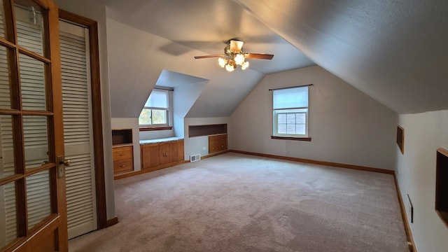 additional living space with light colored carpet, vaulted ceiling, and ceiling fan