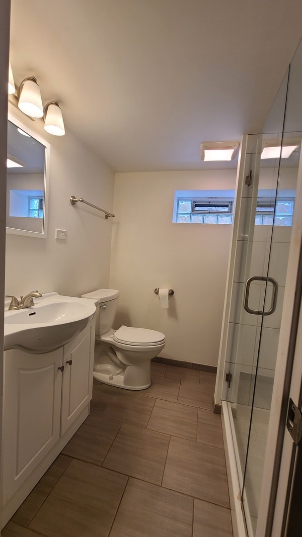 bathroom featuring vanity, toilet, and an enclosed shower