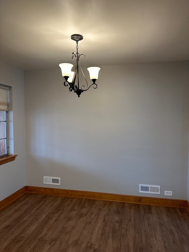 unfurnished room with dark hardwood / wood-style floors and an inviting chandelier