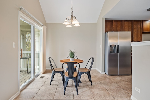 dining space with plenty of natural light, light tile patterned floors, a chandelier, and vaulted ceiling