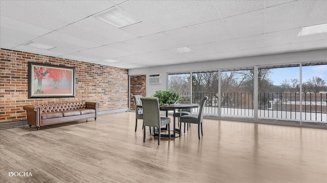 dining area featuring brick wall, a healthy amount of sunlight, and light wood-type flooring