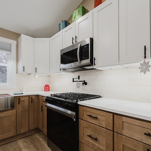 kitchen featuring decorative backsplash, white cabinets, range with gas stovetop, and dark hardwood / wood-style floors