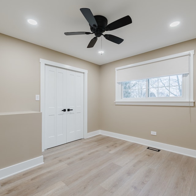 unfurnished bedroom with multiple windows, ceiling fan, a closet, and light wood-type flooring