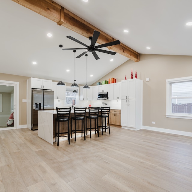 kitchen featuring vaulted ceiling with beams, a wealth of natural light, a center island, and stainless steel appliances