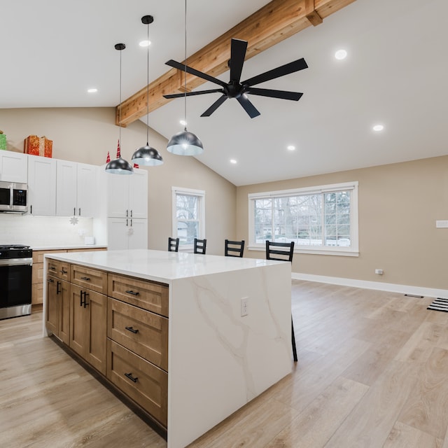 kitchen featuring vaulted ceiling with beams, decorative light fixtures, appliances with stainless steel finishes, and light hardwood / wood-style flooring