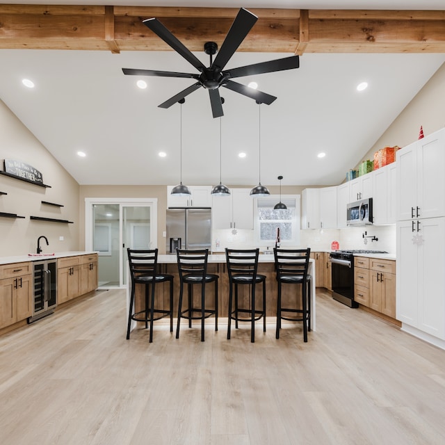 kitchen featuring white cabinetry, stainless steel appliances, wine cooler, a spacious island, and decorative light fixtures