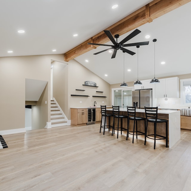 kitchen featuring beamed ceiling, stainless steel fridge, a center island, and light hardwood / wood-style floors