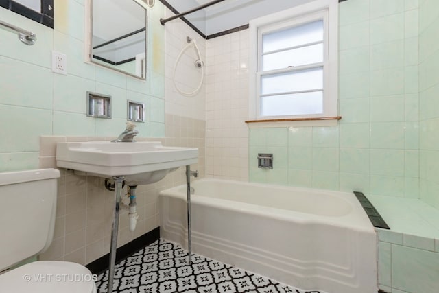 full bathroom with tiled shower / bath, toilet, and tile walls