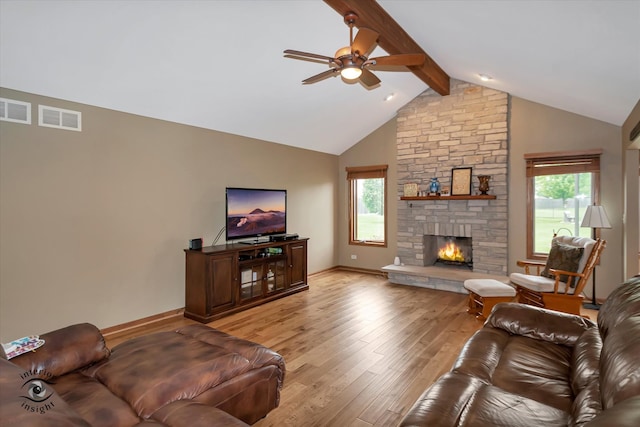 living room with a stone fireplace, ceiling fan, vaulted ceiling with beams, and light wood-type flooring