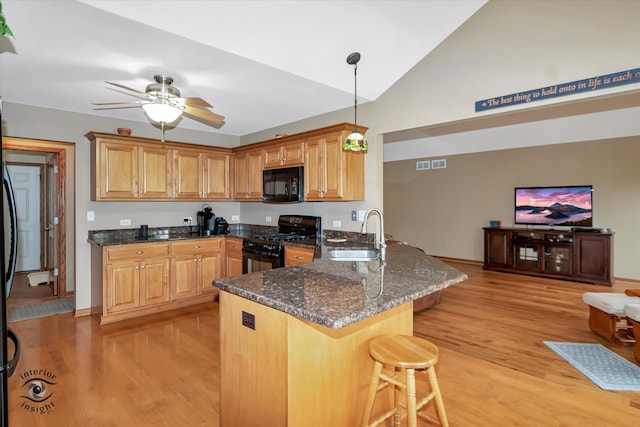 kitchen with kitchen peninsula, sink, black appliances, pendant lighting, and light hardwood / wood-style flooring