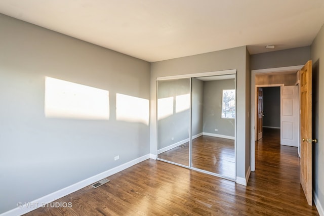 unfurnished bedroom featuring dark hardwood / wood-style floors and a closet