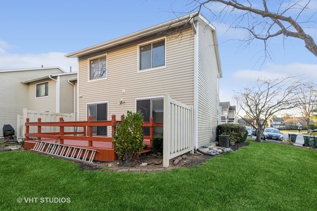 rear view of property with a wooden deck and a lawn