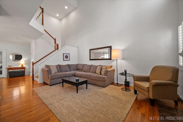 living room with light wood-type flooring and a towering ceiling