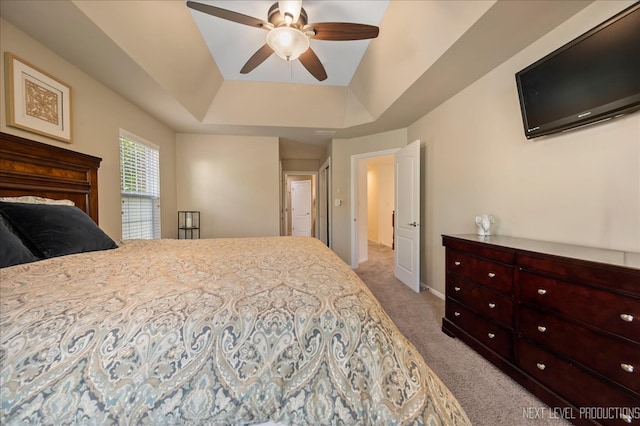 bedroom featuring a raised ceiling, ceiling fan, light colored carpet, and vaulted ceiling