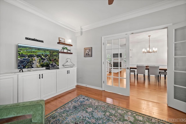 interior space featuring ceiling fan with notable chandelier, light wood-type flooring, and crown molding