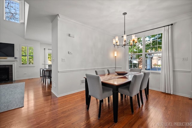 dining space featuring a chandelier, hardwood / wood-style flooring, a fireplace, and crown molding