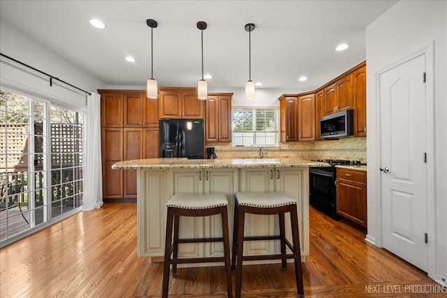 kitchen featuring a center island, light hardwood / wood-style floors, plenty of natural light, and black appliances