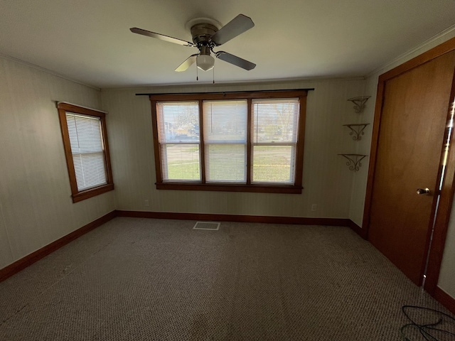 carpeted spare room with ceiling fan and ornamental molding