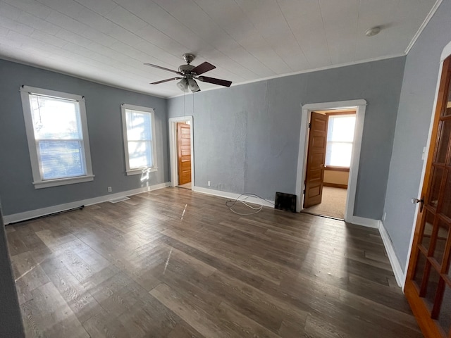 empty room with ceiling fan, crown molding, and dark wood-type flooring