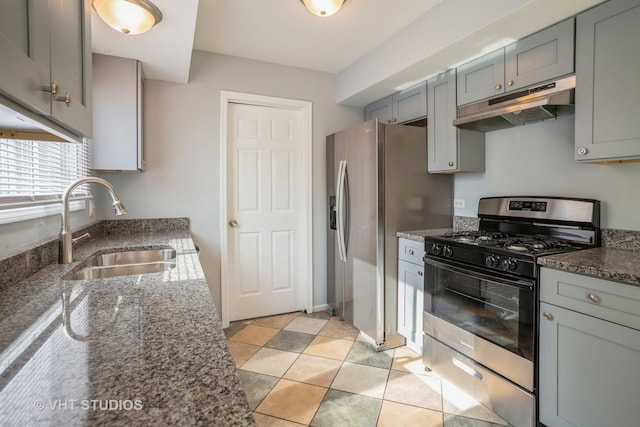 kitchen featuring appliances with stainless steel finishes, dark stone counters, sink, and light tile patterned flooring