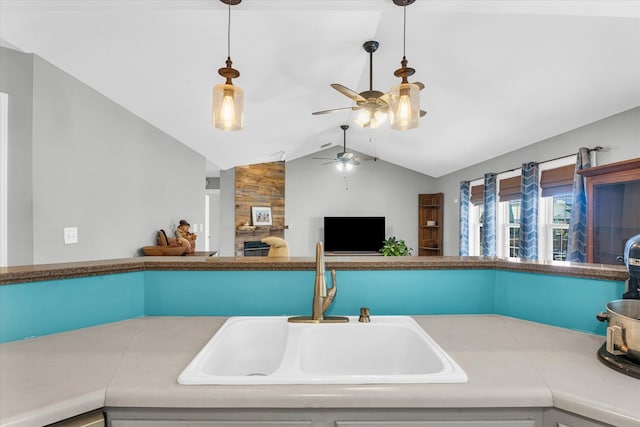 kitchen featuring a stone fireplace, sink, pendant lighting, and lofted ceiling